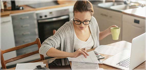 Woman paying her bills online using her computer and online banking.