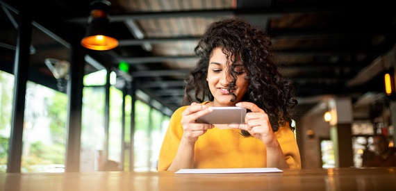 Girl taking a photo of her check to show how remote deposit capture works.