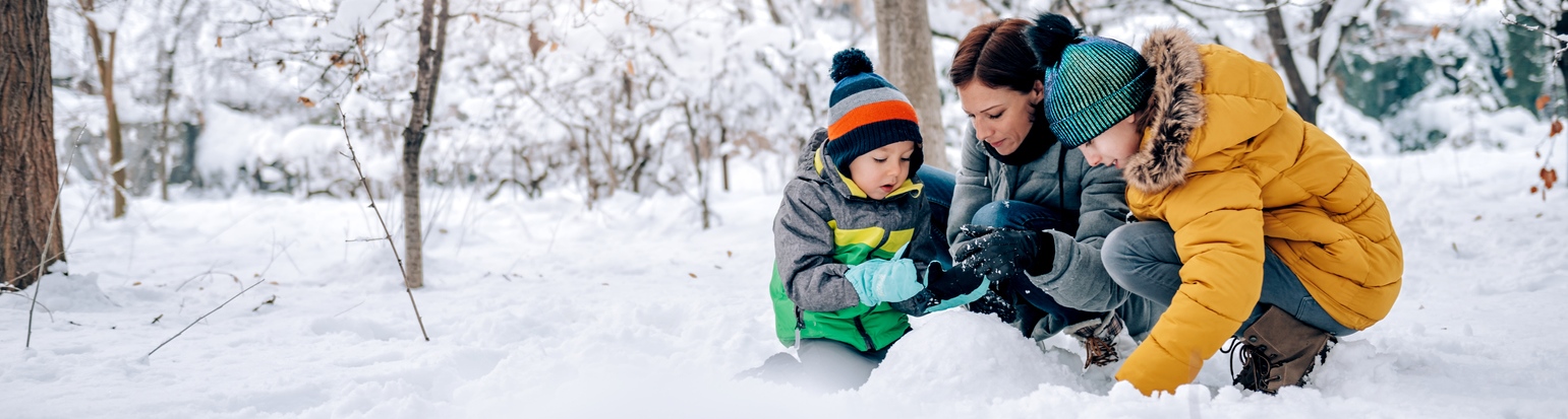 Mother and two children playing in the snow.