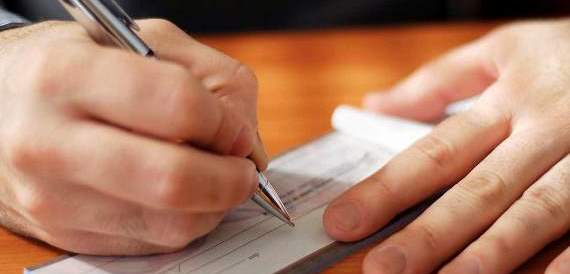 Person writing out a check with pen from their account at Pilot Grove Savings Bank